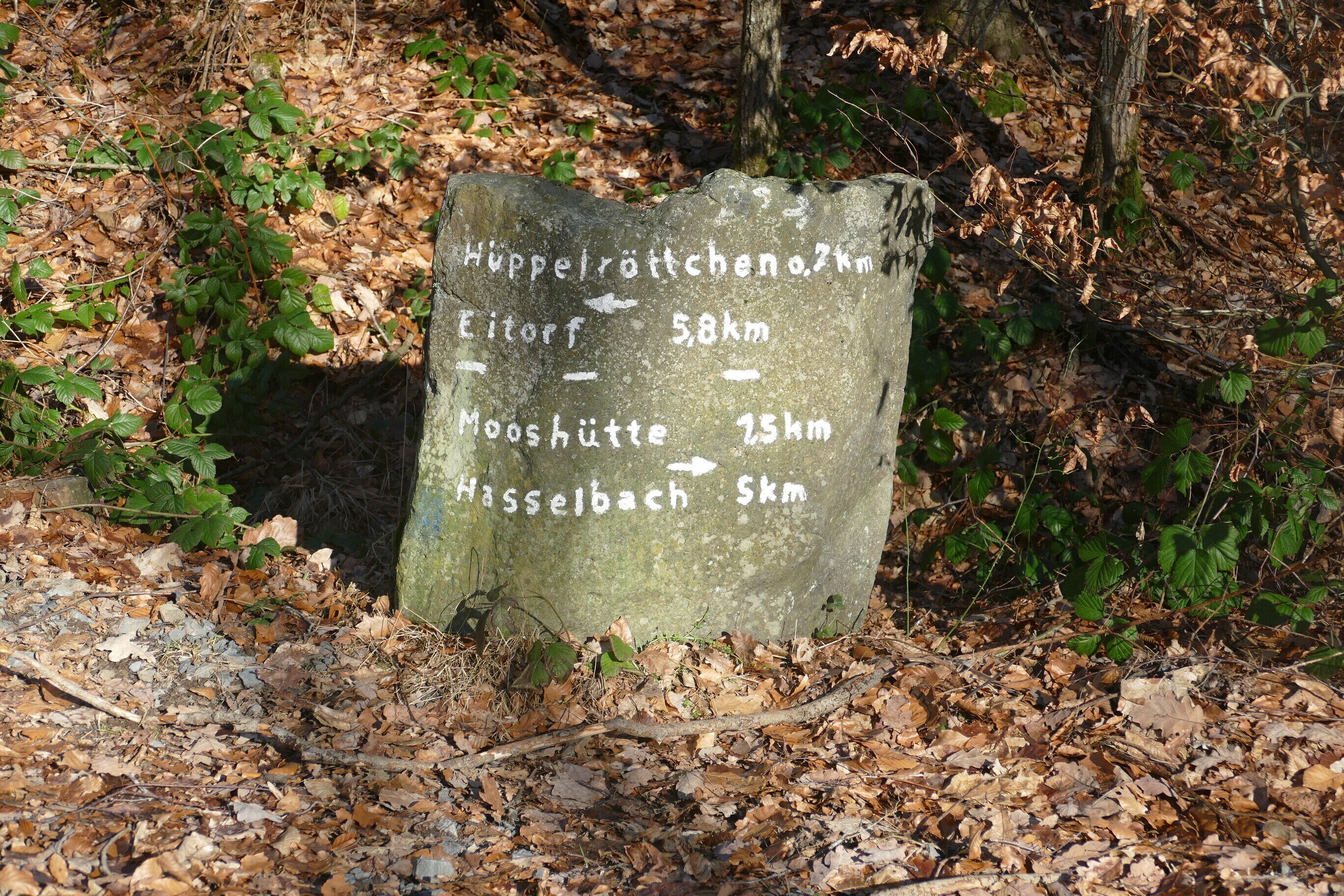 Een stenen bord met routeaanduidingen voor wandelaars.