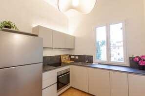 Een moderne keuken met een inbouwoven, een gootsteen en een raam met uitzicht op gebouwen.