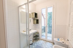 Une salle de bain avec un lavabo, des toilettes et une douche, le tout de couleur blanche.