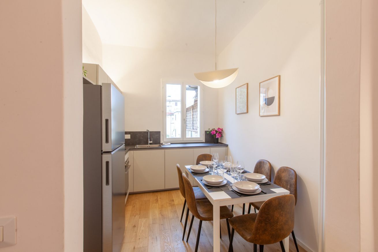 Una cucina compatta con zona pranzo, una finestra e una lampada a sospensione.