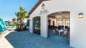 Un bar et un salon appelés « Tu Casa », avec des places assises à l’extérieur et une piscine en arrière-plan.