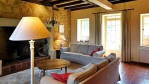 A cozy living room with a stone wall, a fireplace, a sofa, a table, and a lamp.