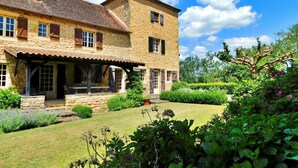 A stone building with a covered patio and a well-maintained garden.