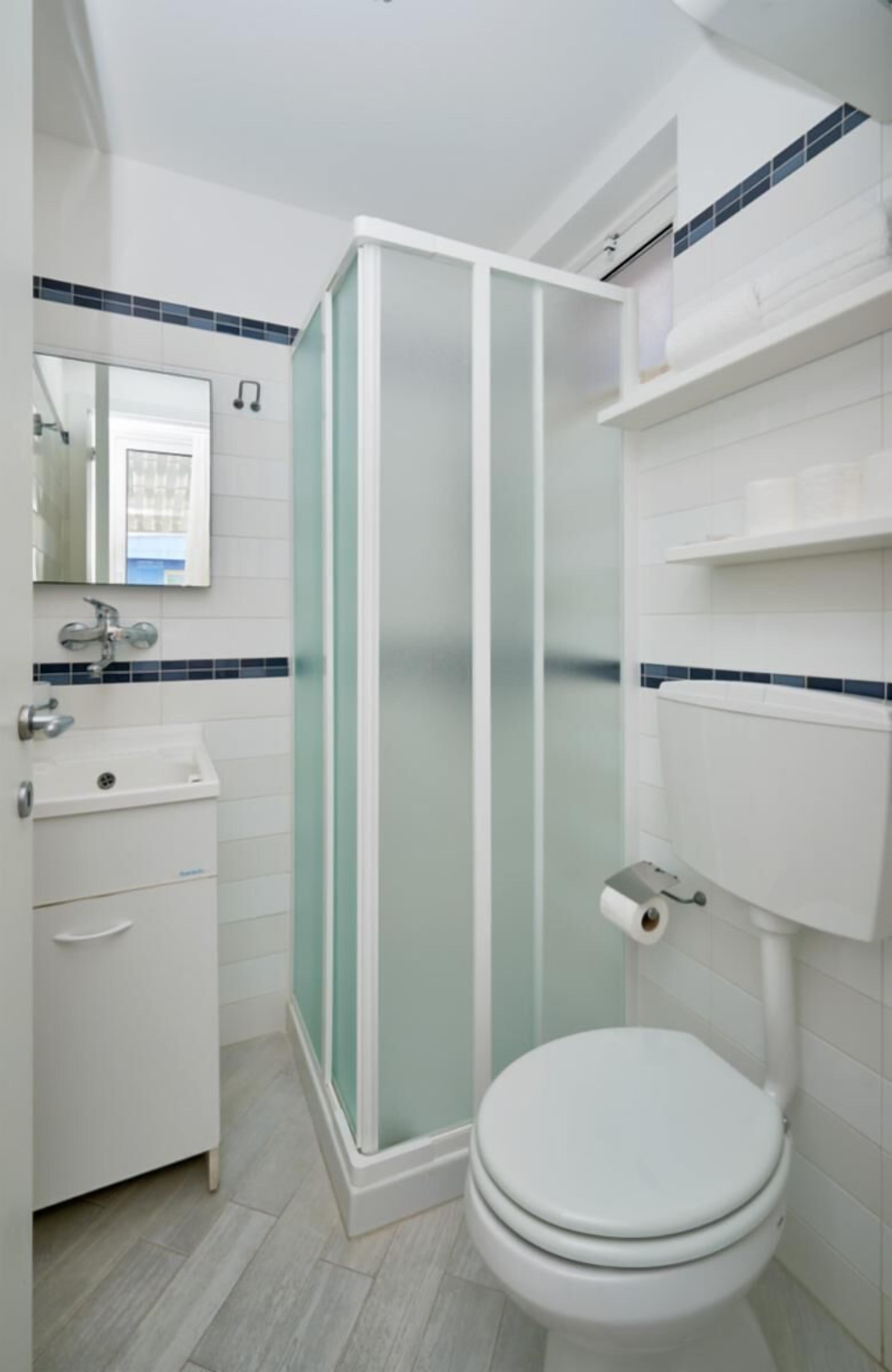 A bathroom with a toilet, sink, and shower enclosure.