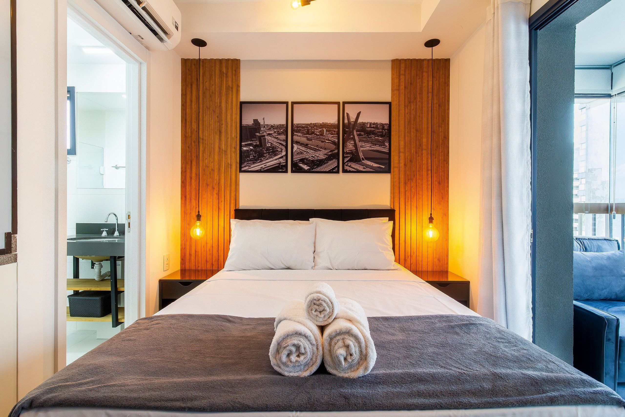A hotel room with a bed, a nightstand, a wall-mounted picture, and a window.