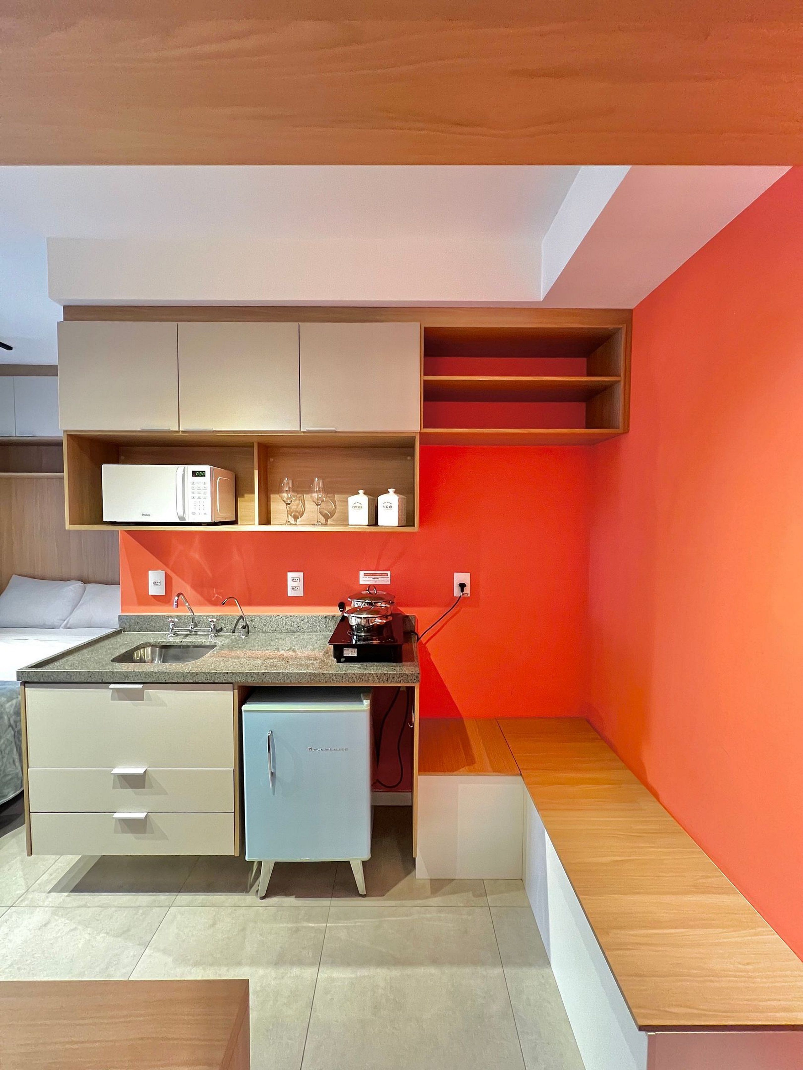 Una cocina compacta con electrodomésticos integrados, un lavamanos y una encimera.