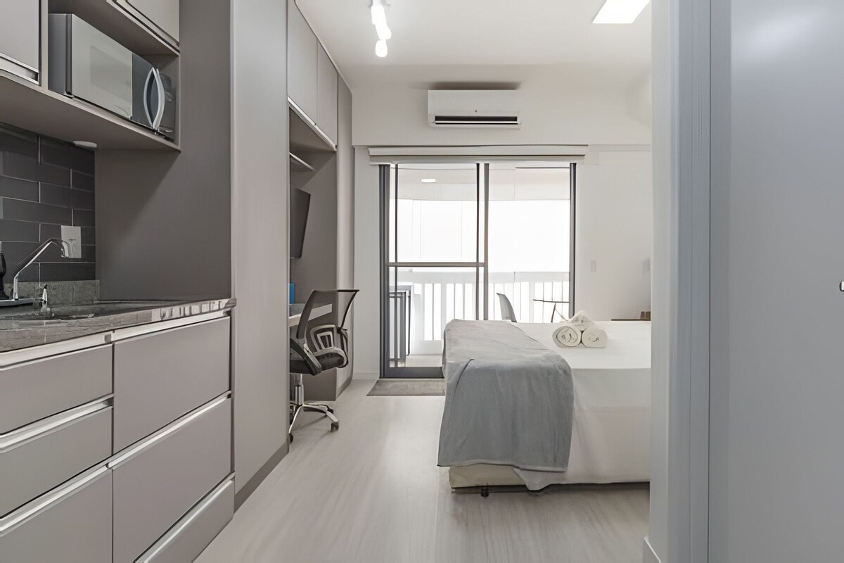Een moderne hotelkamer met een kitchenette, een bed en uitzicht op de omgeving.