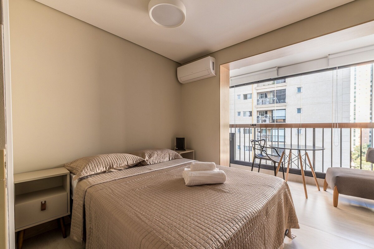 Een slaapkamer met een bed, nachtkastjes, een raam en een balkon.
