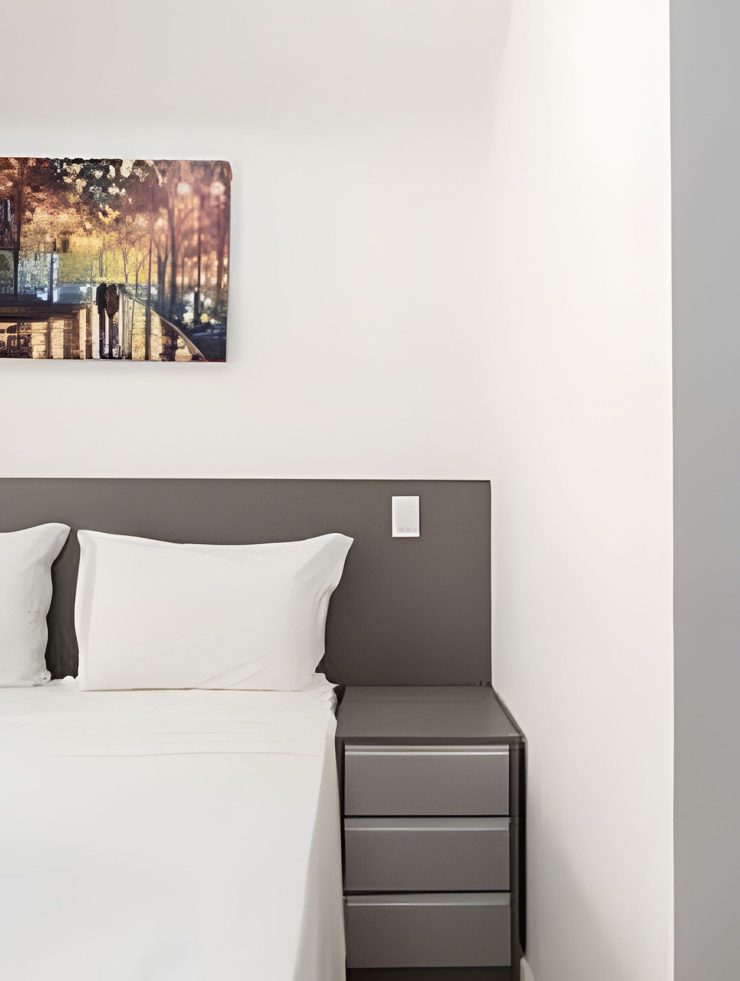 Une chambre à coucher avec un lit, une table de chevet et un tableau accroché au mur.