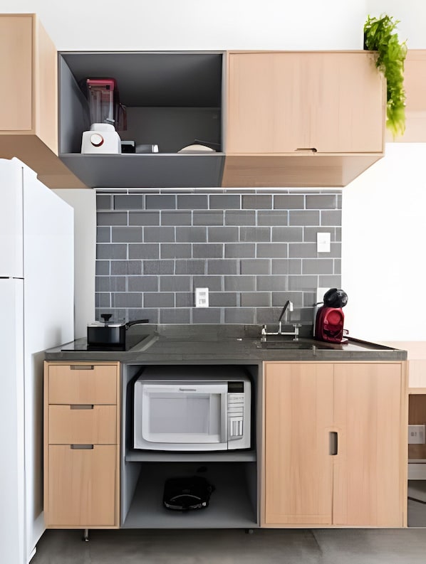 A compact kitchen with a microwave, a blender, and a sink.