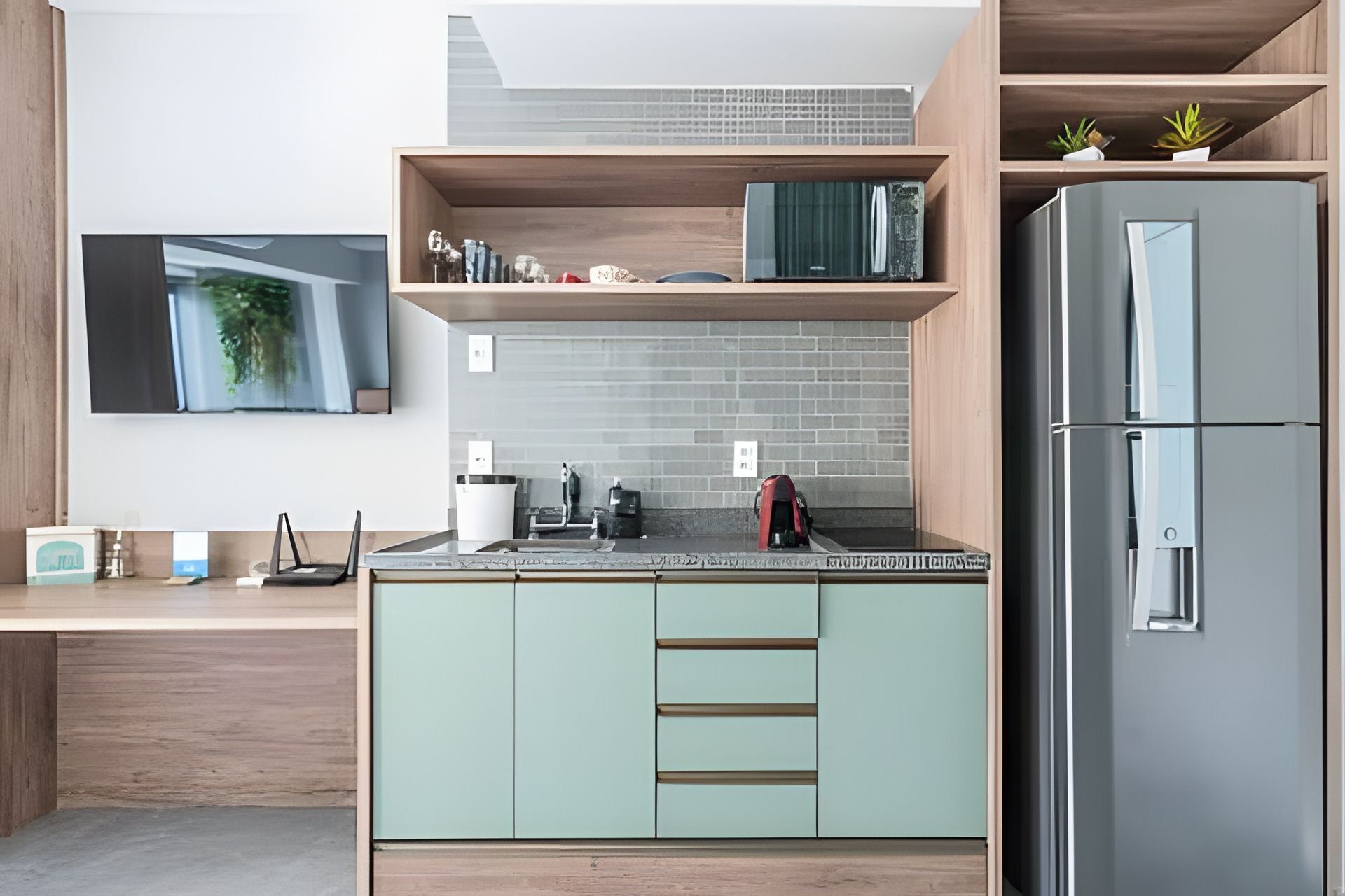 A modern kitchen with a built-in refrigerator, a wooden countertop, and a wall-mounted TV.