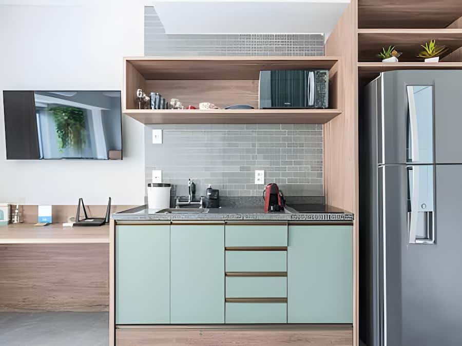 Una cucina moderna con frigorifero integrato, piano di lavoro in legno e televisore a parete.