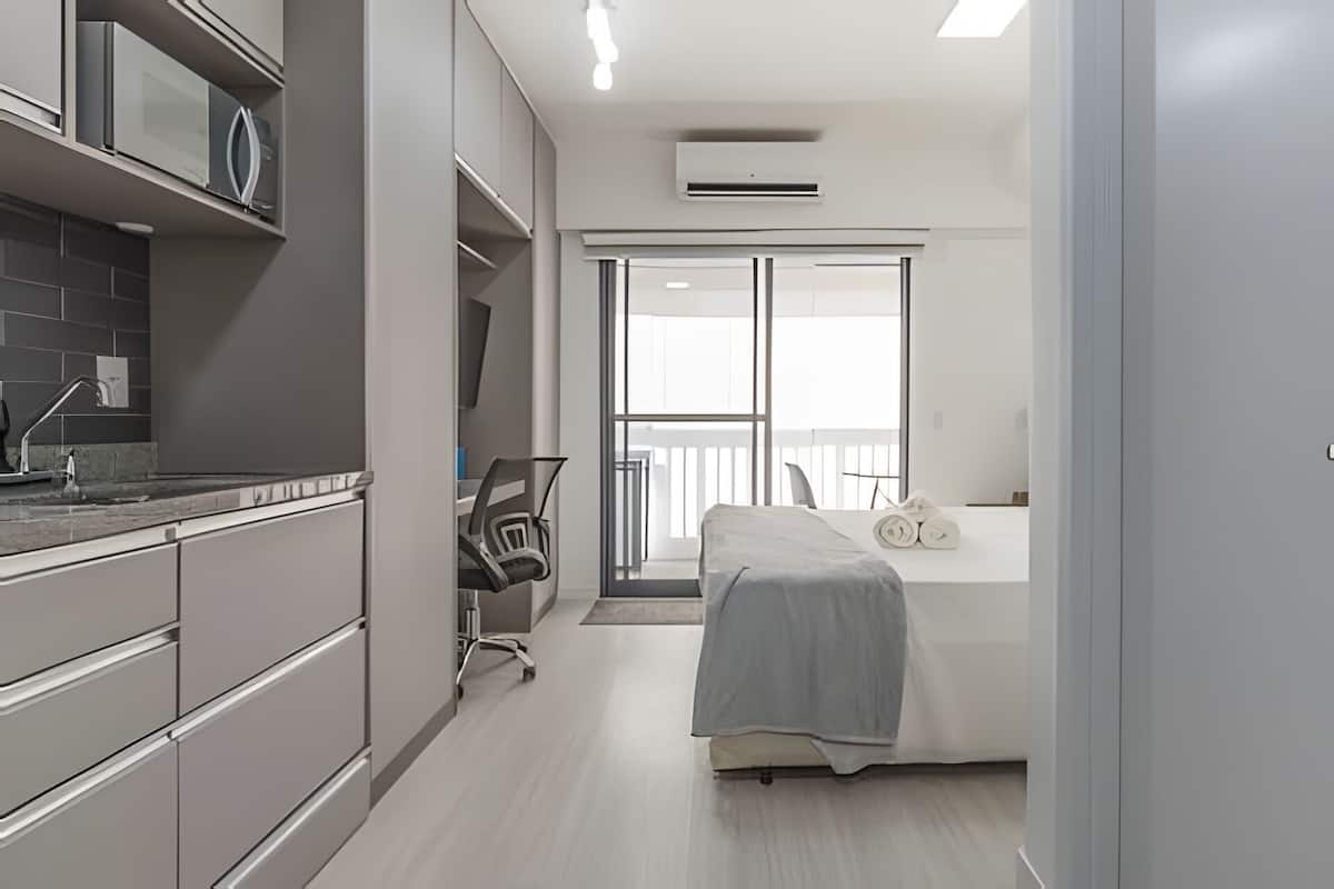 Una habitación de hotel moderna con kitchenette, cama y vistas al exterior.