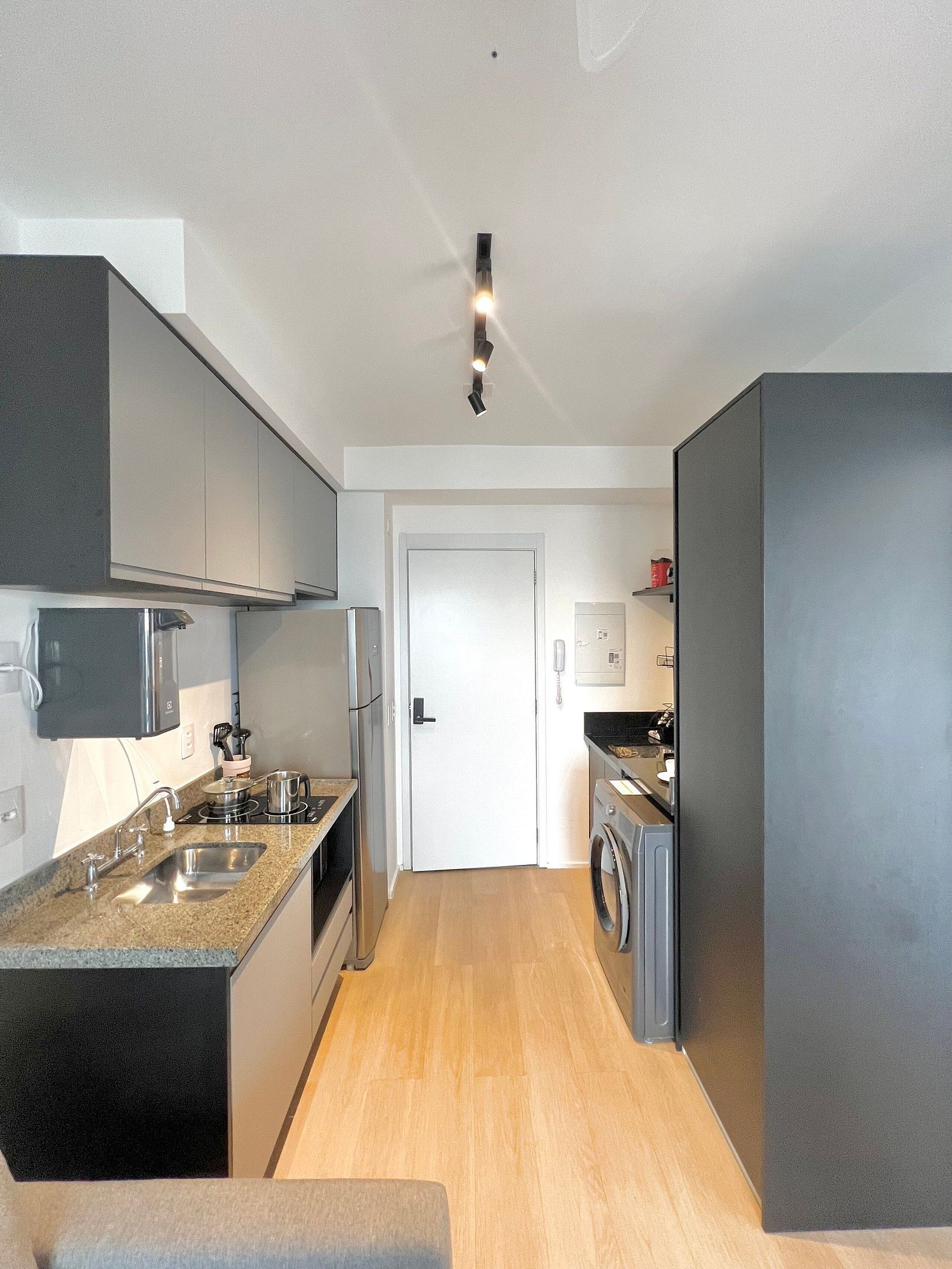 A compact kitchen with a microwave, stove, sink, and a washing machine.