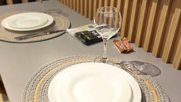 A table set with a white plate, a wine glass, cutlery, and a remote control.