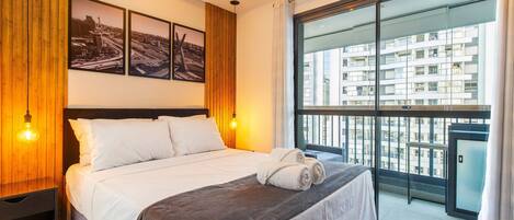 Habitación de hotel con una cama grande, vista a la ciudad por la ventana y un cuadro enmarcado en la pared.
