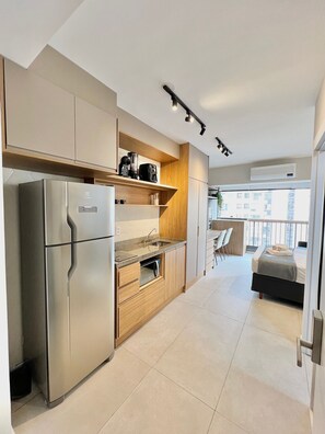 A modern kitchen with a built-in refrigerator, wooden cabinets, and a countertop. - Innvista Uwin Brooklin (São Paulo)
