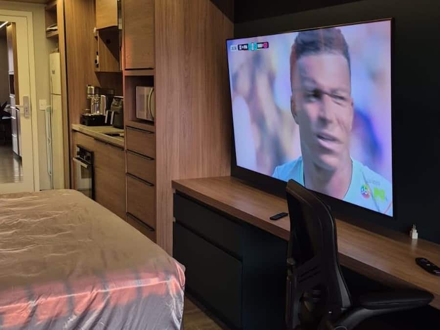 Une chambre à coucher moderne avec un lit, un bureau et un téléviseur.