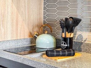 A kitchen counter with a kettle, a cutting board, a towel, and a utensil holder. - Innvista Uwin Brooklin (São Paulo)