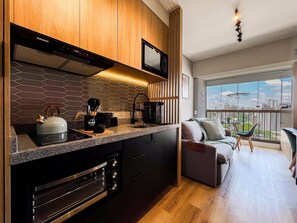 Una cocina moderna con estufa integrada, microondas y armarios negros.