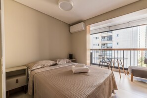 A bedroom with a bed, bedside tables, a window, and a balcony. - Innvista Uwin Brooklin (São Paulo)