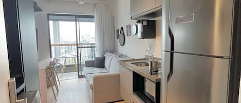 A modern kitchen with a built-in oven, a large refrigerator, and a dining area with a sofa and chairs.