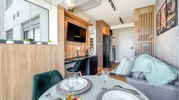 Un comedor moderno con una mesa redonda, sillas y un televisor montado en la pared.
