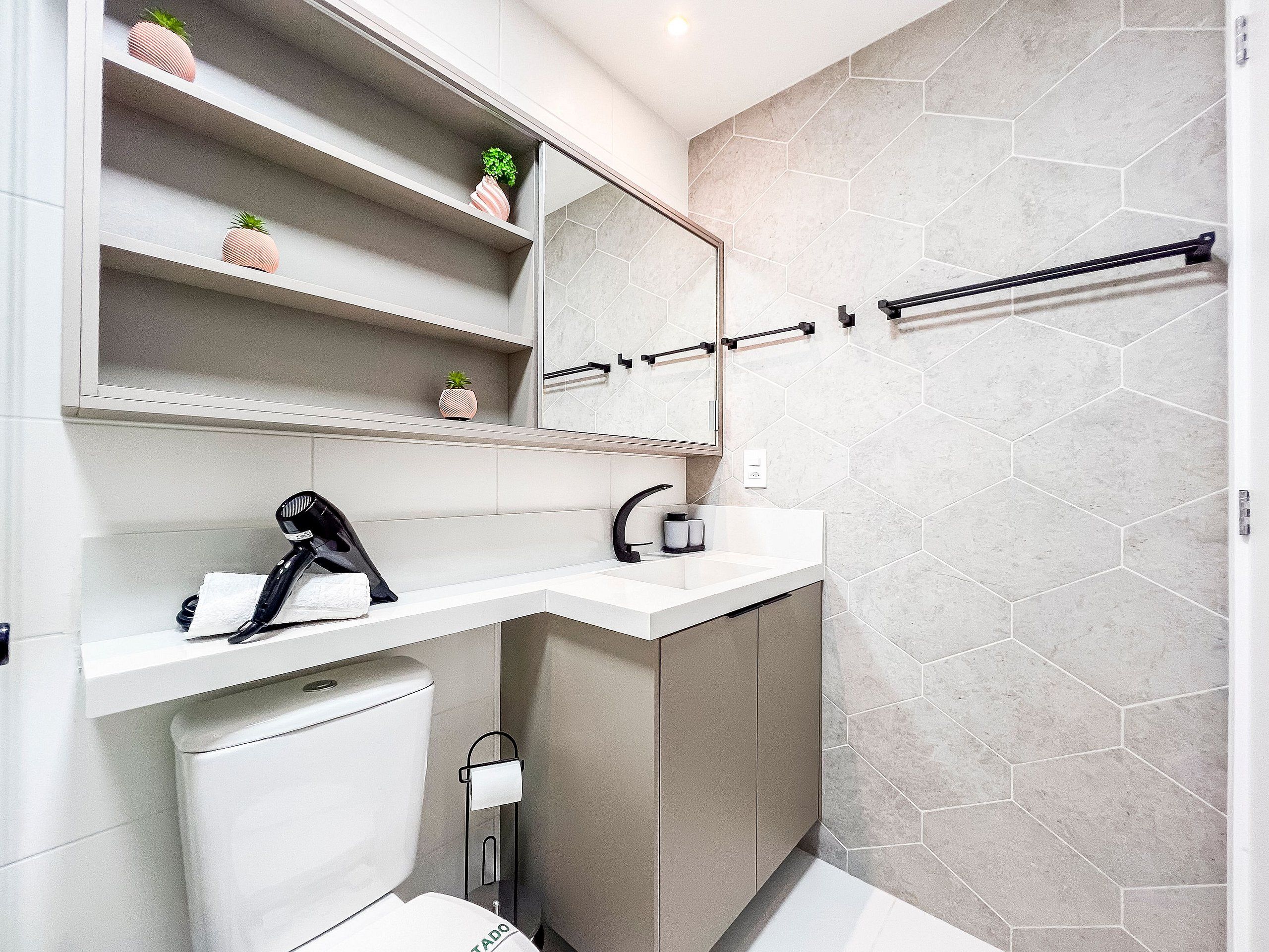 A modern bathroom with a white sink, a mirror, a towel rack, and a toilet.