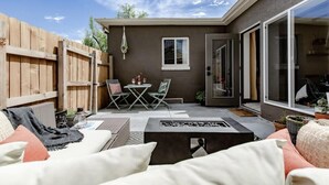 Un patio con cerramiento de madera, una mesa con sillas y una chimenea exterior.