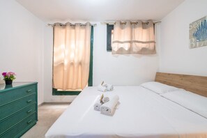 Ein Schlafzimmer mit einem Bett, zwei Vorhängen und einem Schrank sowie einer Wanddekoration.