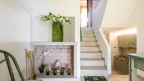 A staircase with a white wall and a green chair on the left. - Villa Matilde Dream Oasis (Villasimius)
