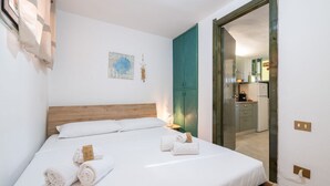 A neatly made bed with rolled towels, a wooden headboard, a teal cabinet, and a small wall decoration. - Villa Matilde Dream Oasis (Villasimius)