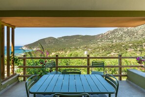 A balcony with a table and chairs, overlooking a mountainous landscape and the sea. - Villa Matilde Dream Oasis (Villasimius)