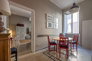 A dining area with a round table and four red chairs, a white cabinet, and a window with natural light.
