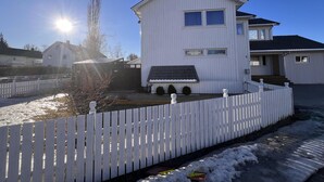 A two-story white building with a fenced yard and a clear sky. - Brand new and Private Studio Apartment! (Bodo)