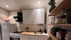 A modern kitchen with white cabinets, a stainless steel sink, and a wooden countertop. There are various kitchen appliances, including a stove and an oven. - Brand new and Private Studio Apartment! (Bodo)