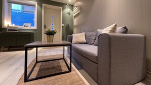 A modern living room with a grey sofa, a small table, and a potted plant. - Brand new and Private Studio Apartment! (Bodo)