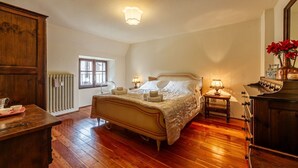 Un dormitorio con una cama de madera, mesitas de noche con lámparas, un radiador y una ventana.