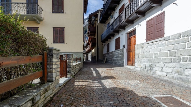 Una estrecha calle adoquinada bordeada por edificios con balcones y contraventanas de madera.