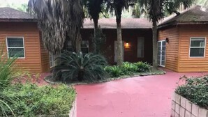 A pathway leading to a building with a red roof and wooden siding.