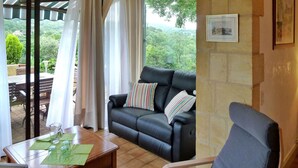 A living room with a black leather sofa, a wooden coffee table, and a view of greenery outside. - Beautiful home in Domme with WiFi (Domme)