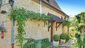 A stone building with a covered entrance, a fire extinguisher, and potted plants. - Beautiful home in Domme with WiFi (Domme)