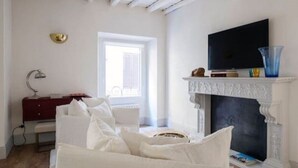 A room with a white fireplace, a television mounted above it, and a red cabinet to the left. - Luxury & Charm between Pantheon and Spanish Steps (Roma)