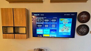 Un téléviseur fixé au mur affiche l’interface Roku TV et propose différents services de diffusion en continu.