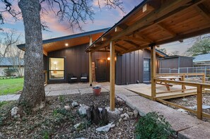 A modern building with a covered patio, a large tree, and a small garden area. - Aggie Fan Cave - Minutes to Kyle Field+BigBackyard (College Station)