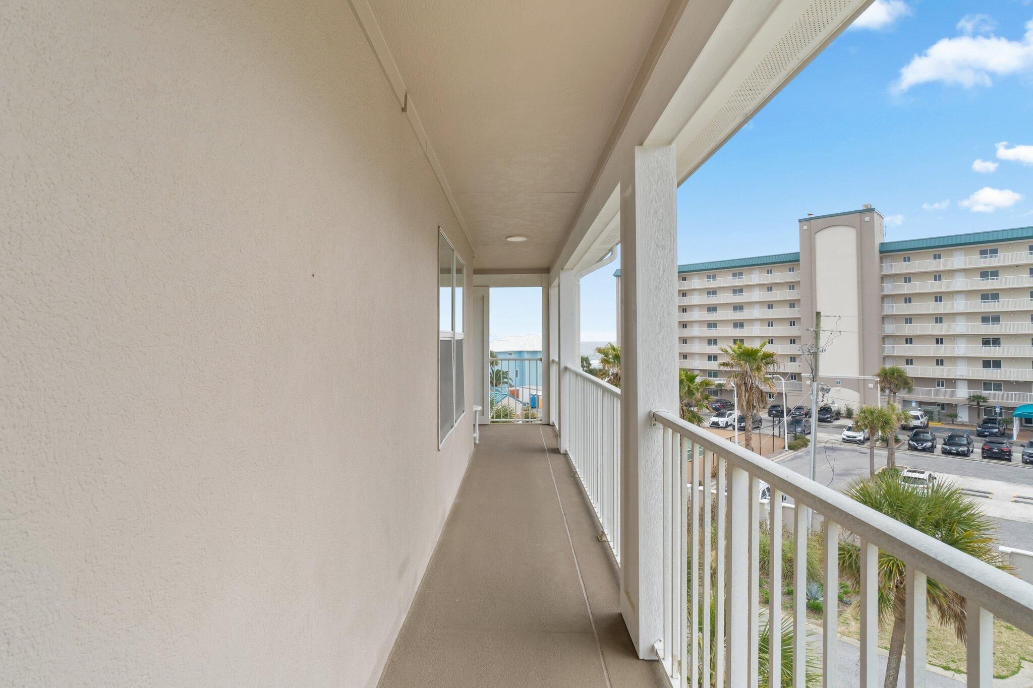 A balcony with a view of a parking lot and a building.