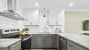 A modern kitchen with white cabinets, a stainless steel range, and a wooden floor. - Grand Caribbean East 417 (Pensacola)