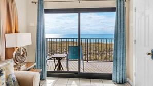 Uma varanda com vista para o mar, uma mesa e uma cadeira.