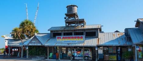 A building with a sign reading "FLOUNDERS Chowder House" and a water tower.