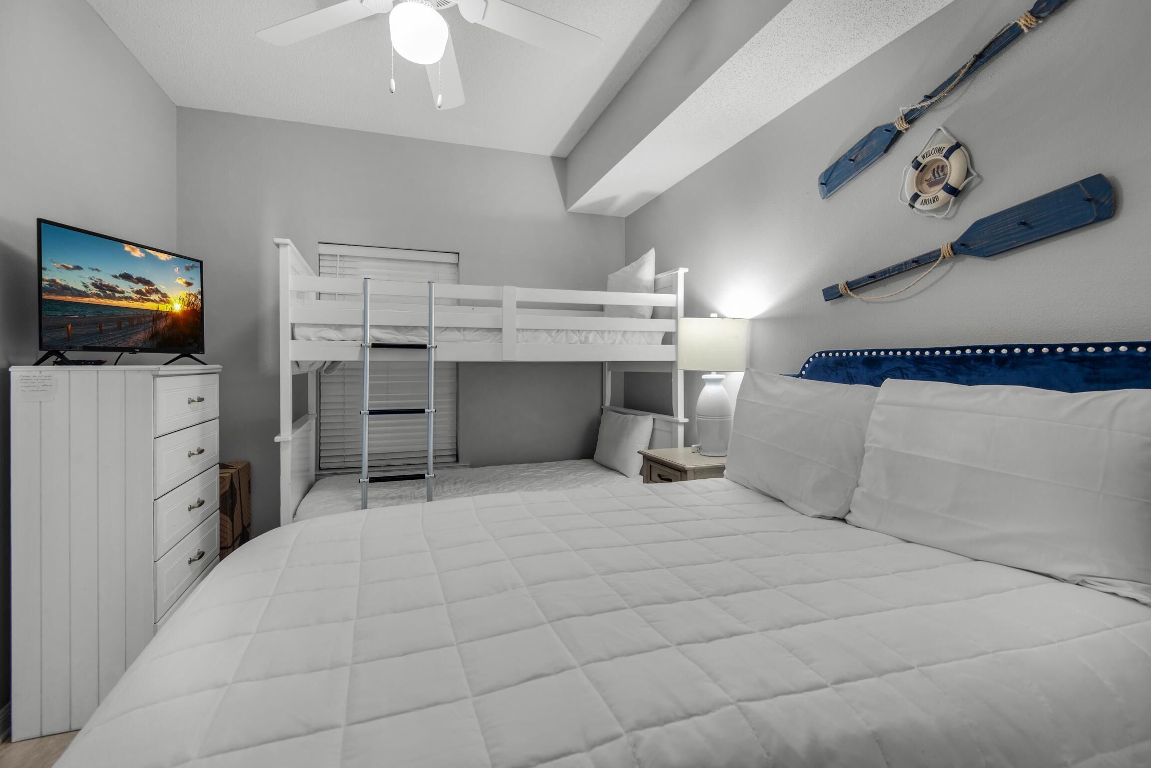 A bunk bed room with a TV, a desk, and a lamp.